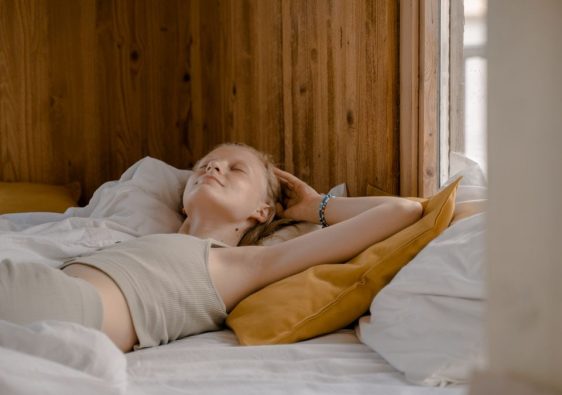 A woman enjoys a tranquil moment lying on her back in a cozy wooden bedroom.